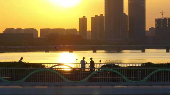 日落时分金黄色河水桥上观看夕阳的人剪影