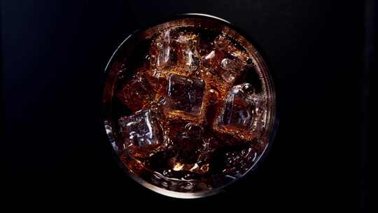 俯拍往加冰块的玻璃杯里倒可乐