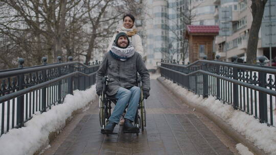 女士推着轮椅上的男子在公园聊天