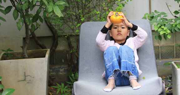 小女孩将柿子顶头上玩