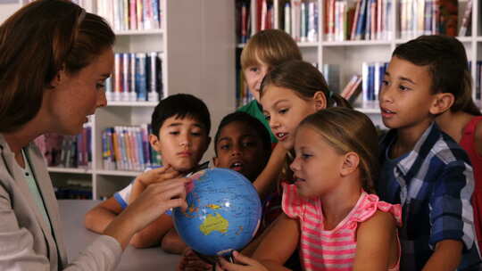 教师在图书馆协助学童阅读地球仪视频素材模板下载