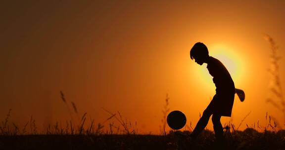 小男孩在夕阳下颠足球