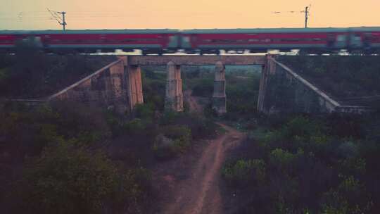 一架印度铁路客运列车在旧混凝土铁路桥上快