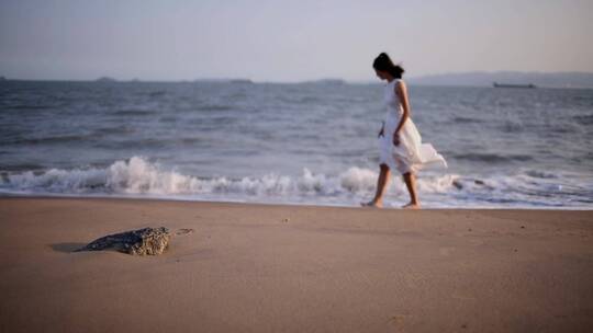 白衣裙子少女再海边慢慢行走