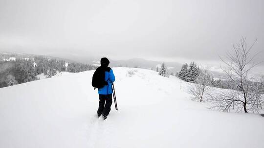 雪地里拿着相机和三脚架的摄影师