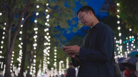 一名亚洲男子站在霓虹灯闪烁的城市街道上，