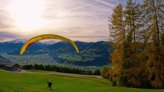 4K滑翔伞在蓝天白云草地树林间飞行