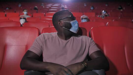 黑人男子戴口罩在影院里看电影