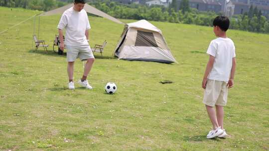 年轻家庭户外露营，父子踢足球慢镜头