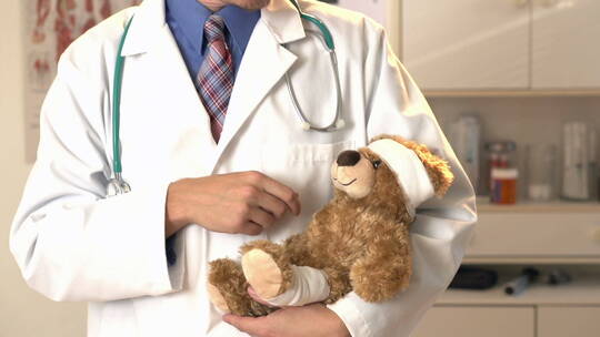 带着泰迪熊的儿童医生对着镜头微笑