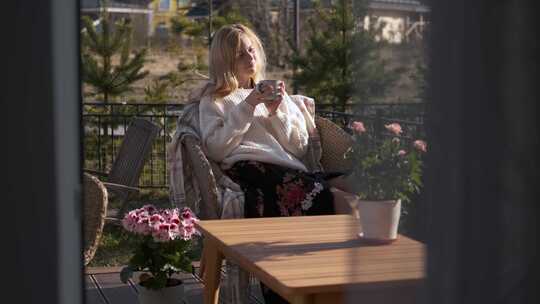 美丽的女人在露台上用鲜花喝茶
