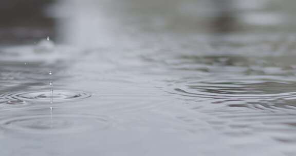 雨滴慢慢落入水坑并产生气泡