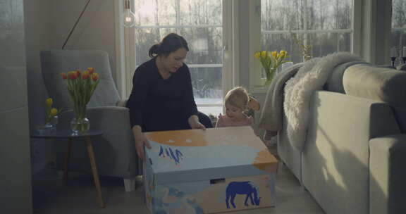 母亲和孩子在舒适的客厅，自然光下拆箱芬兰