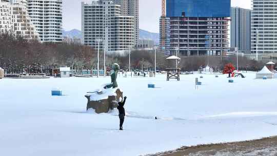 雪地中人物在雕塑旁举手的景象