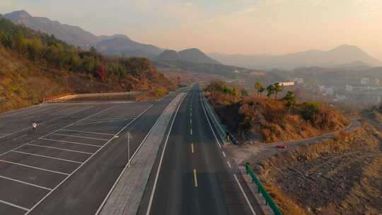 迎着朝霞在空旷山路上行驶的汽车