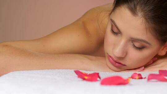 躺在玫瑰花瓣毛巾上放松的女人