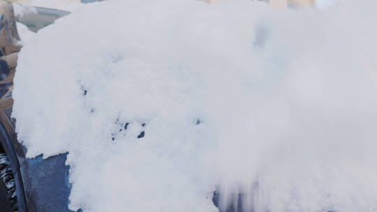一个人拿扫雪器扫车上的雪