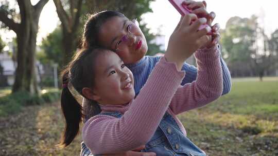 小女孩和妈妈在公园里用手机自拍