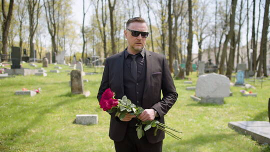 悲伤的男人站在墓地里