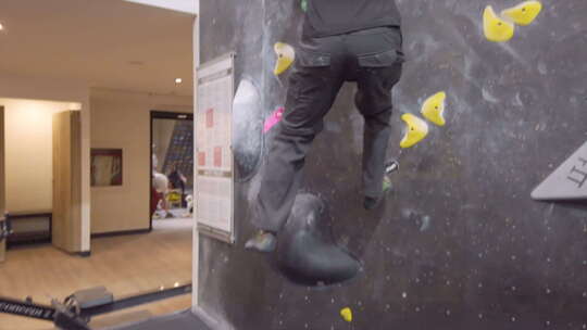 亚洲登山者家伙在健身房爬上室外抱石墙
