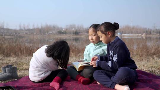 冬季在公园草坪上看书的三个女孩