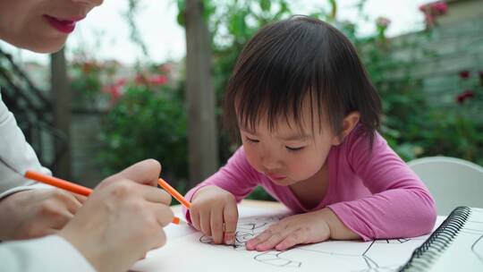 小女孩和妈妈在院子里一起写字画画学习