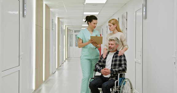 轮椅上的中年男子与护士和同伴在医院