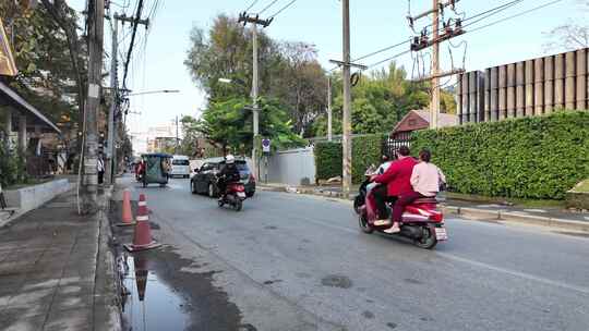 泰国清迈街道上行驶车辆旁的特色建筑