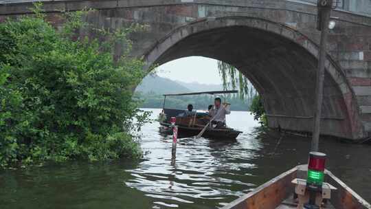 西湖游客乘坐游船经过石拱桥桥洞