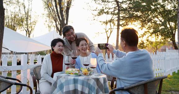 夕阳下中老年朋友在庭院里聚会喝酒干杯