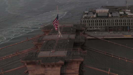 美国航空：布鲁克林大桥上空的美国国旗和曼哈顿东河景特写圆环飞行视频素材模板下载