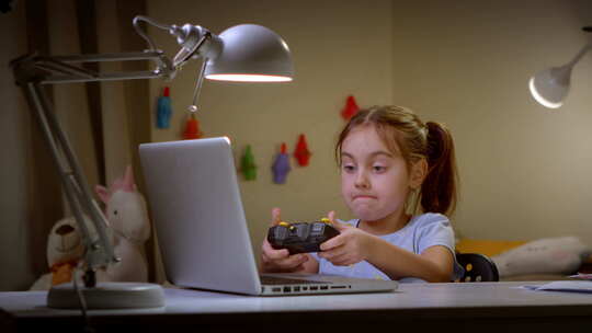 女孩用笔记本电脑和手柄玩游戏