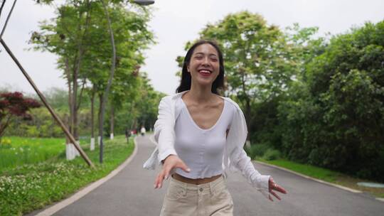 美女快乐奔跑在夏天公园道路上的慢镜头