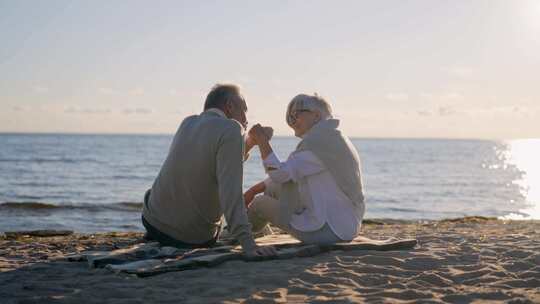 浪漫的老年夫妇坐在海边聊天一起休息男人亲
