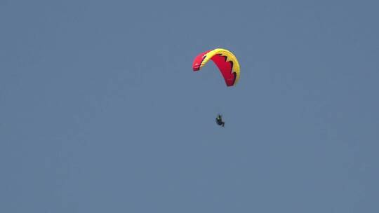天空中坐着红色滑翔伞的人