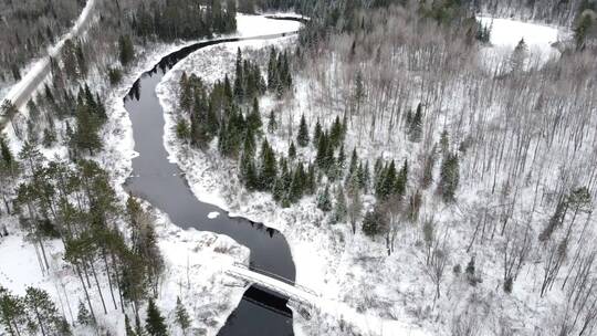 航拍被白雪覆盖的森林与河上的一座桥