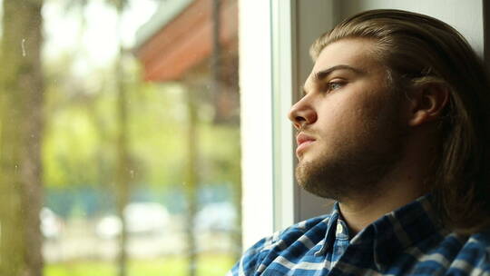 男人坐在窗户旁边沉思