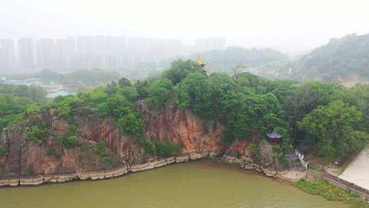 江边岩石上的亭子与远处的城市建筑群