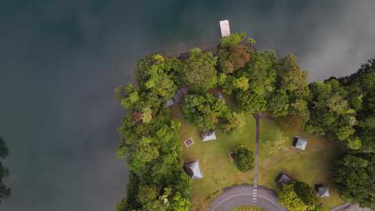 移动无人机视频俯瞰火山口湖旁边郁郁葱葱的公园区域，云层回流