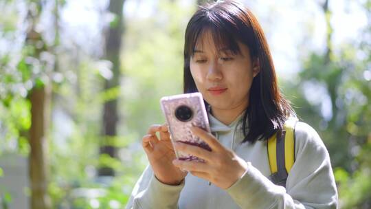 年轻阳光活力女孩春天户外踏青游玩刷手机