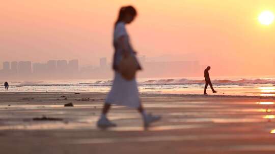 烟台夏天海边落日夕阳，女孩在沙滩上走动