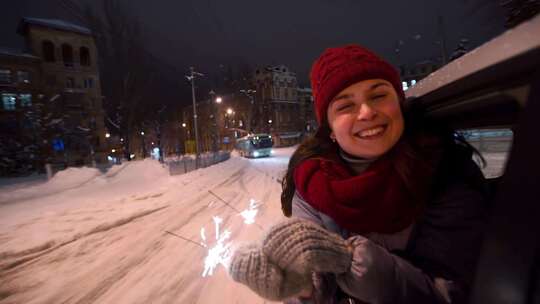 年轻快乐的女人探出车窗，在下雪的冬夜漂亮