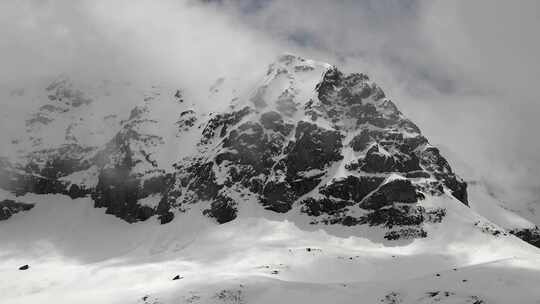 多云冬季的高海拔岩石雪穹顶山峰