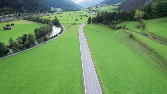 阿尔卑斯山鸟瞰中绿野之间奥地利山谷的空旷道路