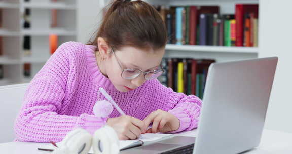 女孩使用笔记本电脑学习做笔记