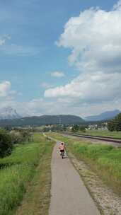 男孩在铁路附近的小路上骑自行车。山景。加