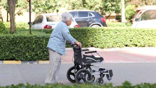 老人推轮椅缓慢的前行走路
