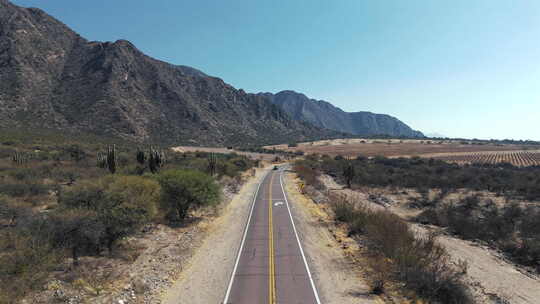 汽车在背景是山脉的偏远沙漠公路上行驶。阿