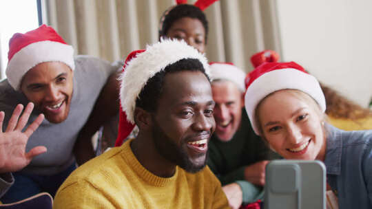 快乐的一群不同的朋友在圣诞派对上使用智能手机进行视频通话