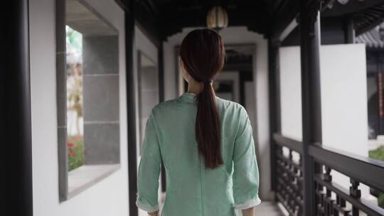 年轻旗袍女子步行穿过中式合院门廊走廊